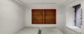 two beds in a small room with wooden shutters