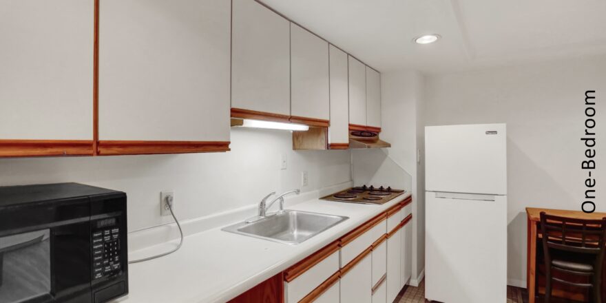 a kitchen with white cabinets and brown flooring