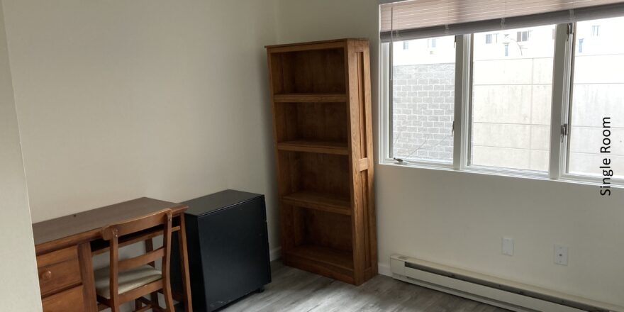 a room with a desk, bookcase and television