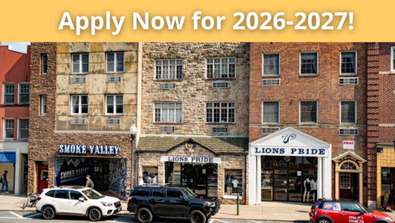 a group of cars driving down a street next to tall buildings