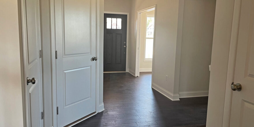 an empty room with white doors and hard wood floors