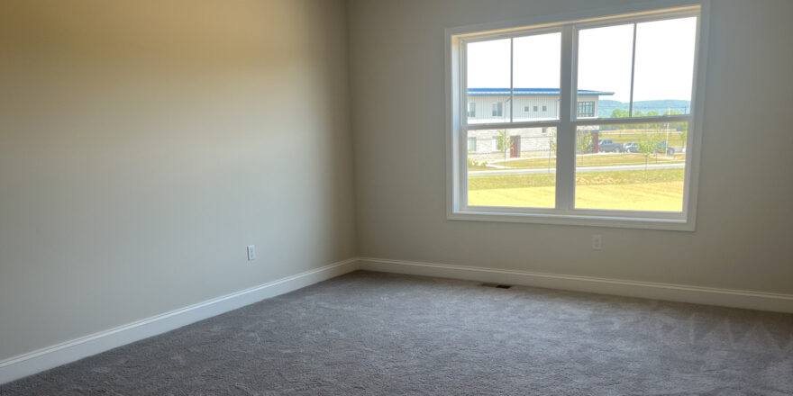 an empty room with a large window and carpet