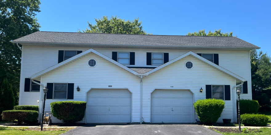a white two story duplex with black shutters