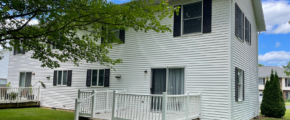 Duplex with white siding, black shutters, a garage, and gray shingles, and a back porch