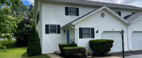 Duplex with white siding, black shutters, a garage, and gray shingles