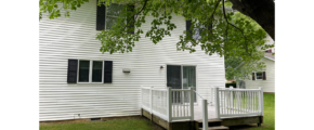 a white duplex with black shutters and a porch