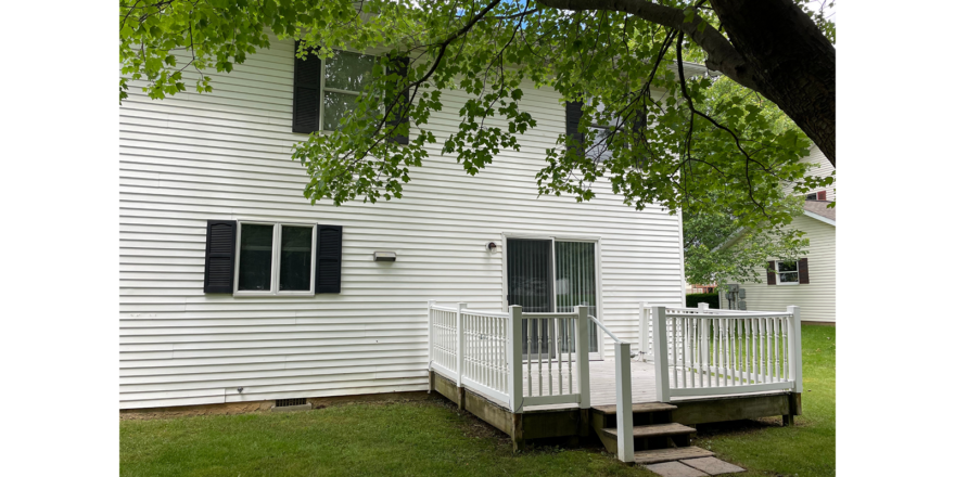 a white duplex with black shutters and a porch