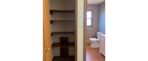 a closet with shelves and a bathroom next to it