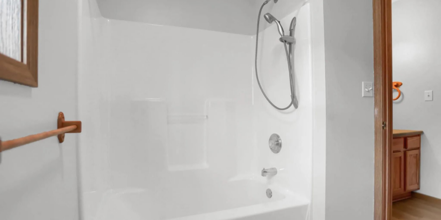 a bathroom with a bathtub, sink, and mirror