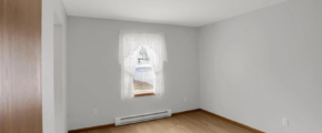 an empty room with wood floors and a window