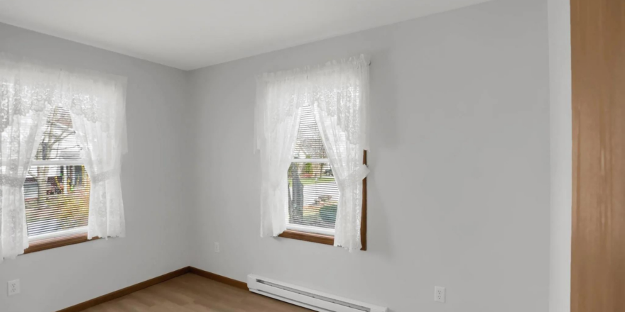 a empty room with two windows and a radiator