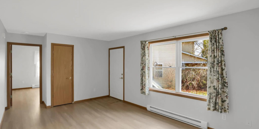 an empty room with wood floors and a window