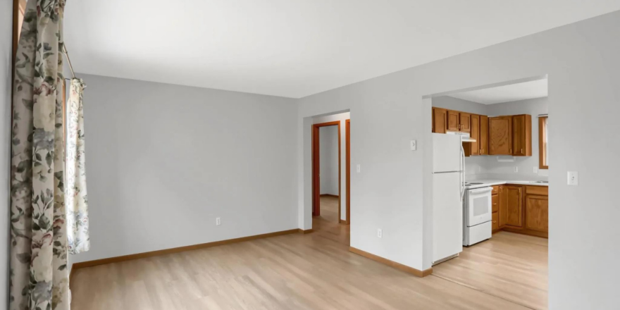 an empty living room with wood floors and white walls