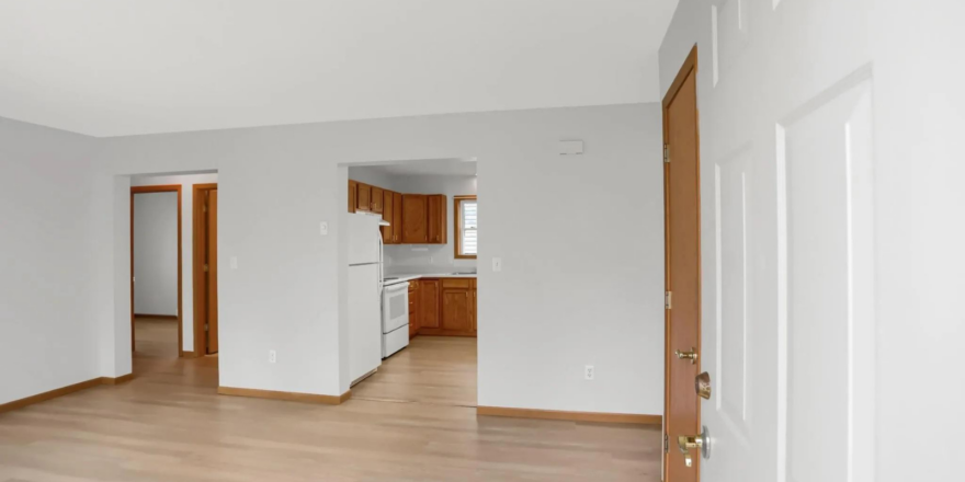an empty living room with wood floors and white walls