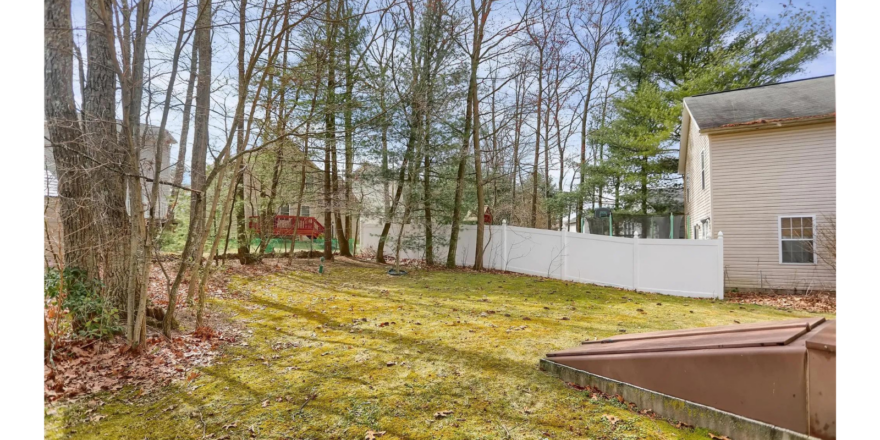 a yard with a fence and trees in the background