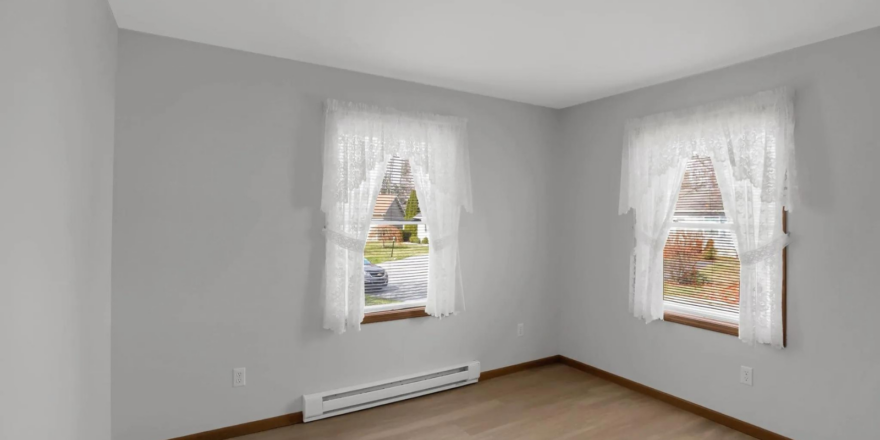 a empty room with two windows and a radiator