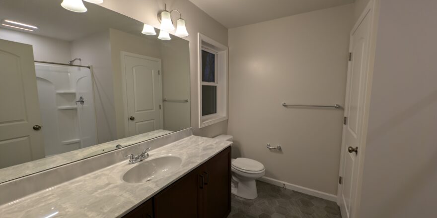 a bathroom with a toilet, sink, and mirror