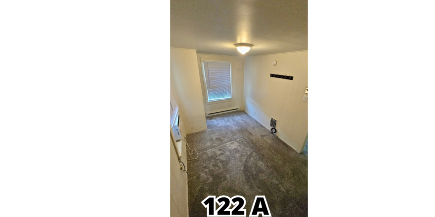 an empty room with wood floors and a window