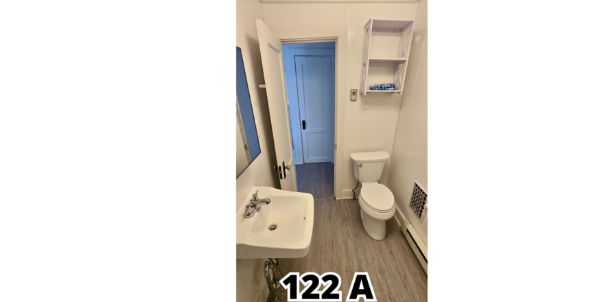 a bathroom with a toilet, sink, and mirror