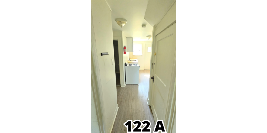 a narrow hallway with a white refrigerator next to it