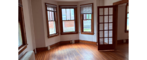 an empty room with wooden floors and three windows
