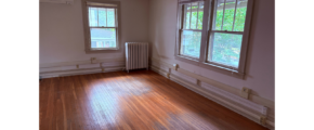 an empty room with a radiator and two windows