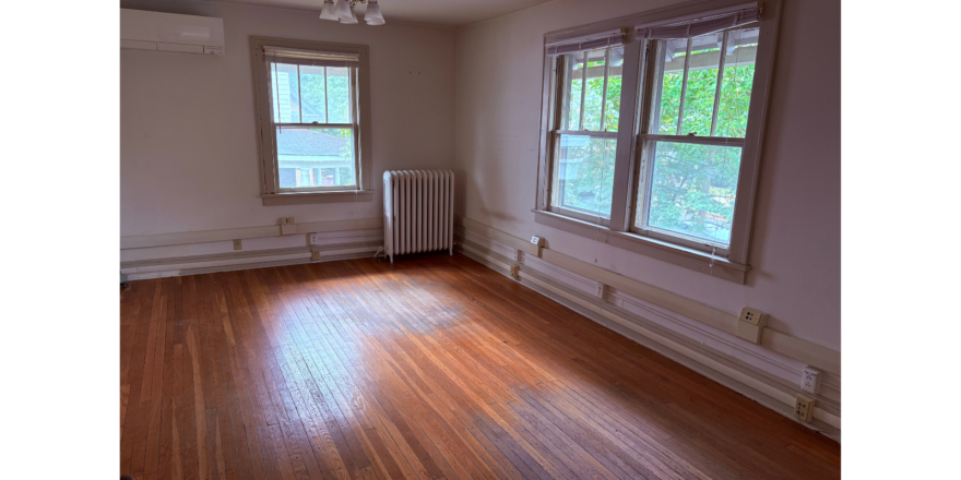 an empty room with a radiator and two windows