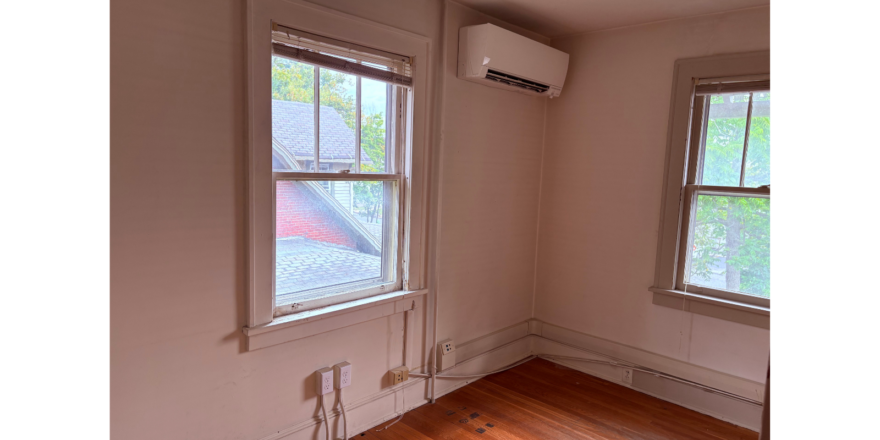 an empty room with two windows and a wood floor