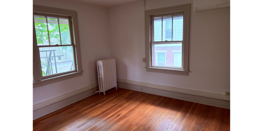 an empty room with two windows and a radiator