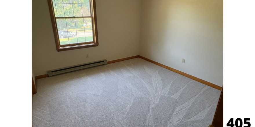 an empty room with a window and a radiator
