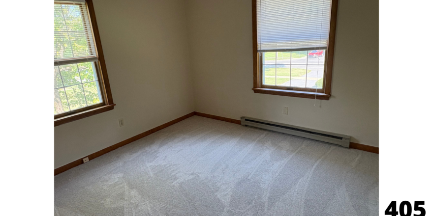 an empty room with two windows and a radiator