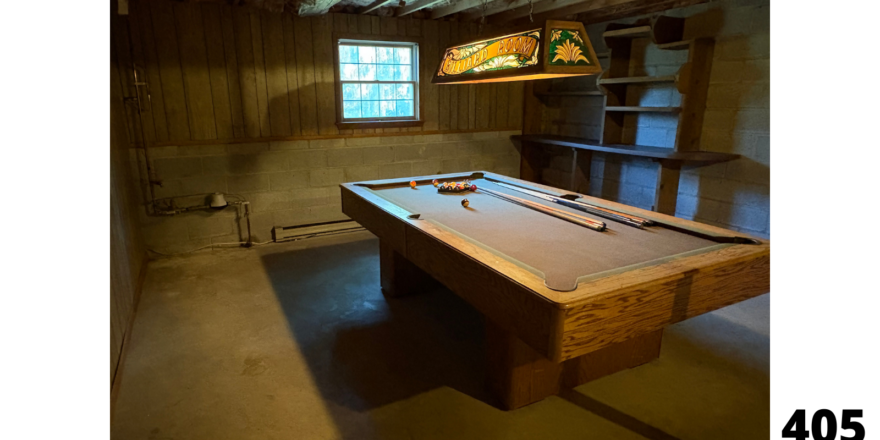 a pool table in a room with a book shelf