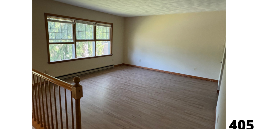 an empty room with a wooden railing and a window