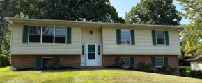 a two story house with green shutters and a white door