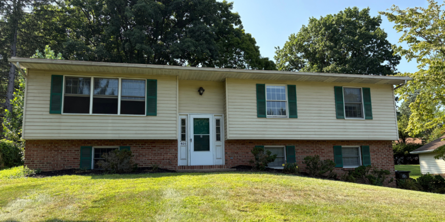 a two story house with green shutters and a white door