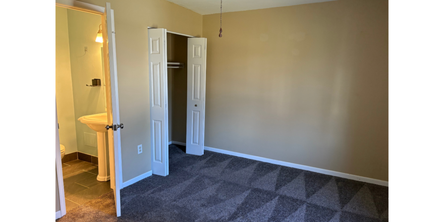 an empty room with a ceiling fan and a door