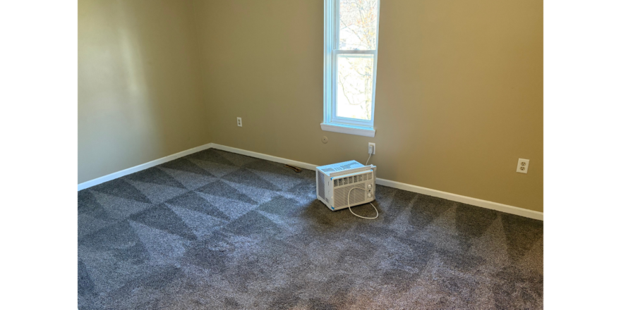 an empty room with a ceiling fan and a window