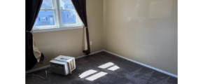 an empty room with a window and a heater
