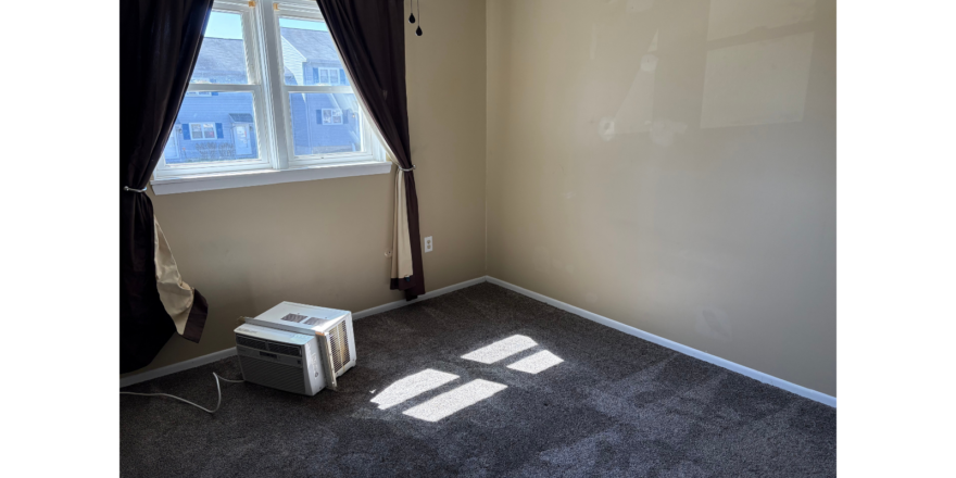 an empty room with a window and a heater