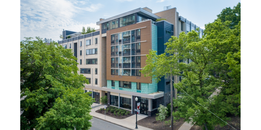 a large multi-faceted building with many windows and a lot of trees in front of it