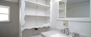 a bathroom with a sink, mirror and shelves