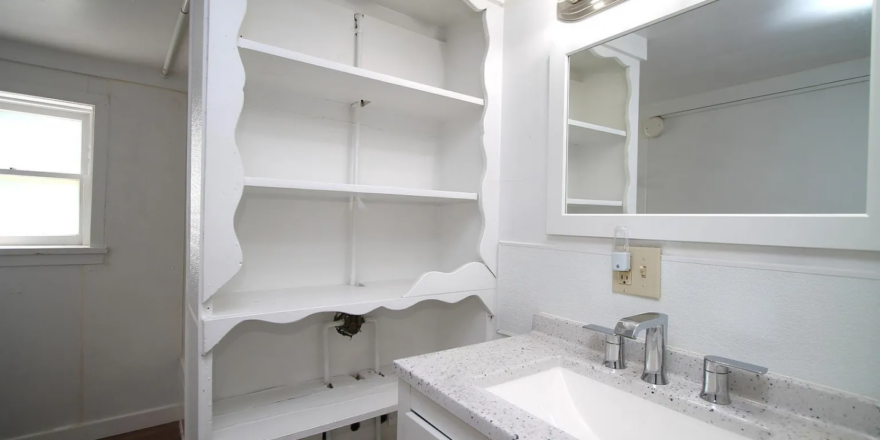 a bathroom with a sink, mirror and shelves