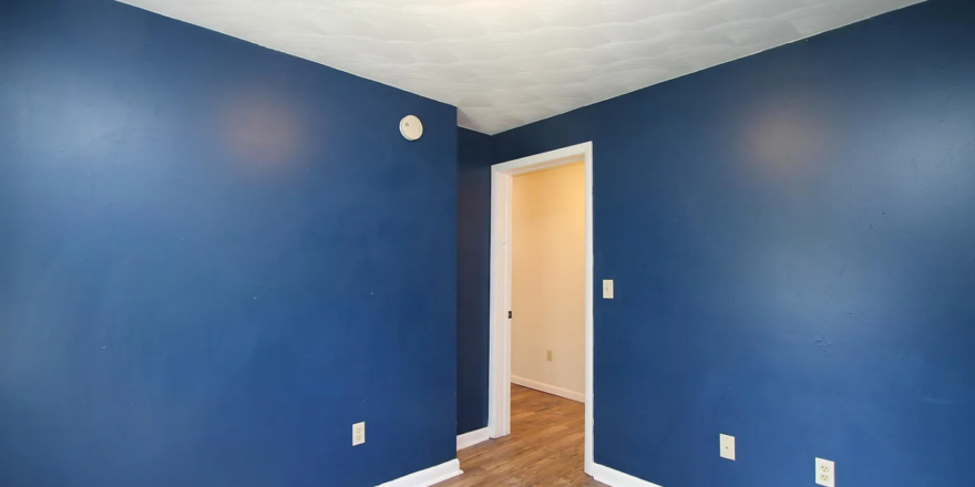 an empty room with blue walls and wood floors