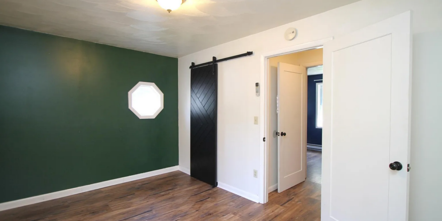 an empty room with green walls and wood floors
