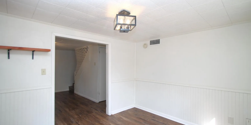 an empty room with hard wood floors and white walls