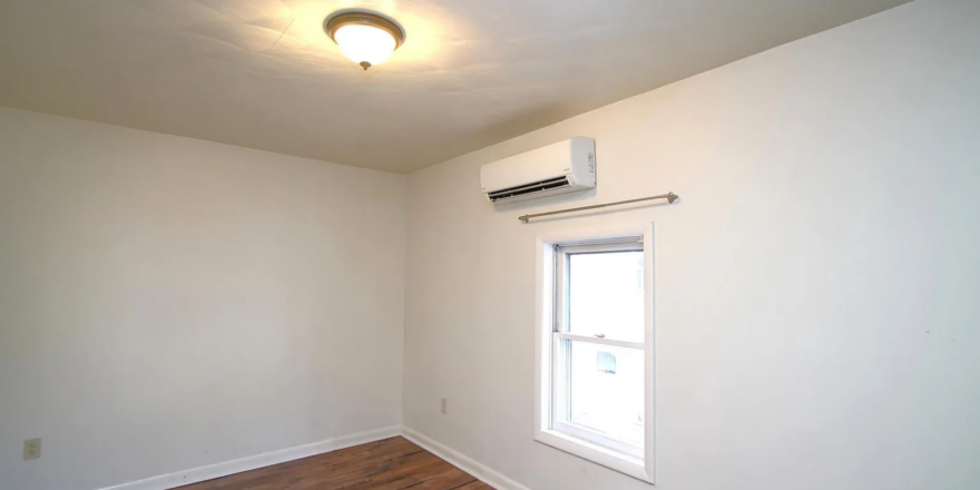 an empty room with hard wood floors and a window