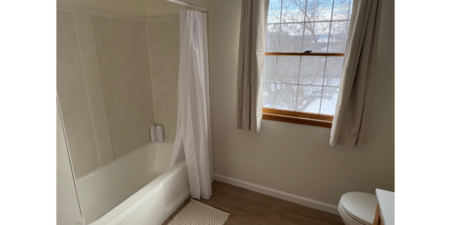 a bathroom with a tub, toilet and window