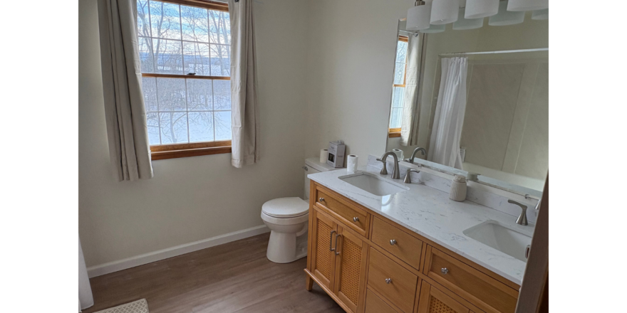 a bathroom with two sinks, a toilet and a window
