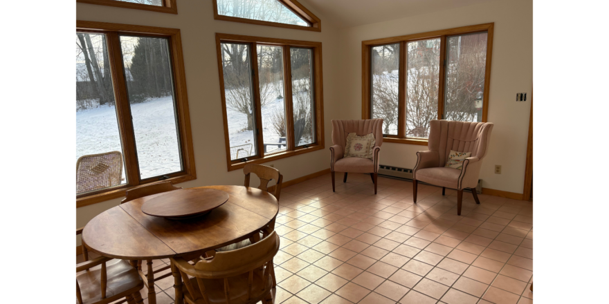 a room with a table, chairs, and a lot of windows