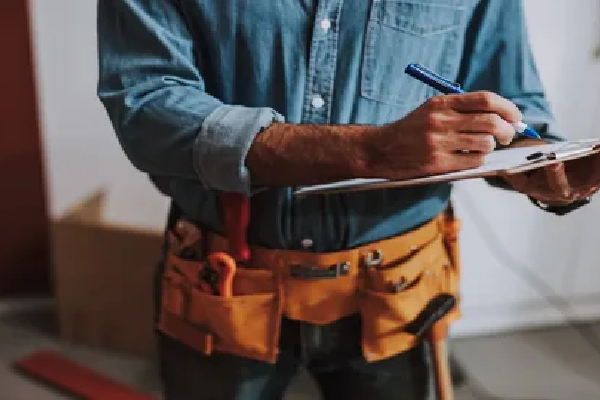 a man in overalls writing on a clipboard